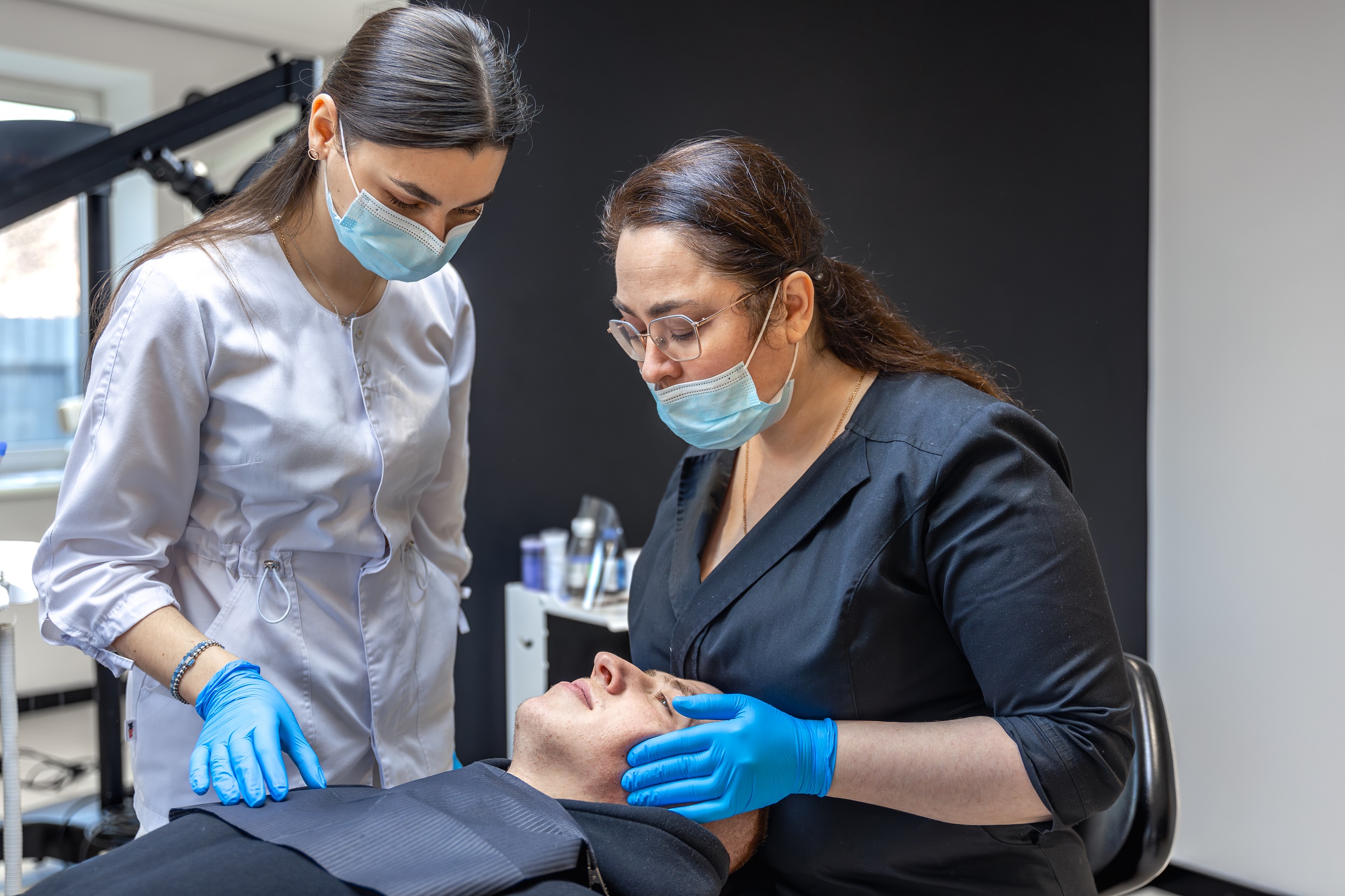 Team of female dentists treating patient's teeth.